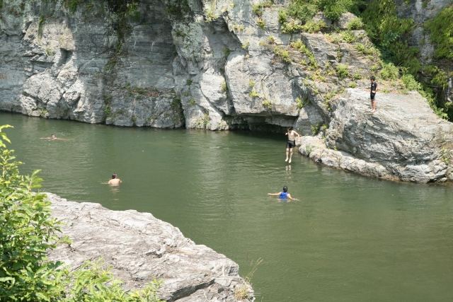 岩場から川に飛び込んで遊んでいる子供たち