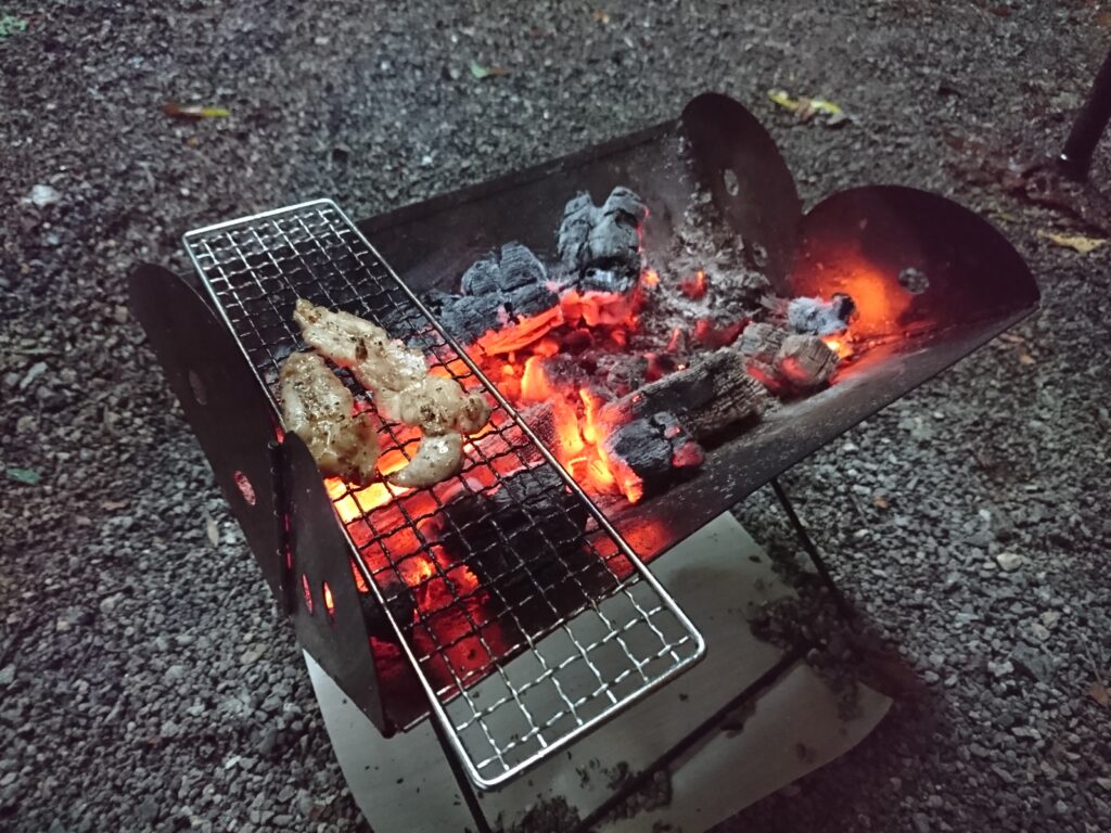 「フラットパックポータブル グリル＆ファイヤーピット」で調理と焚き火をしている画像